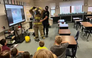 Chief Stocking and Titus (Firefighter EMT) demonstrate donning structure fire gear.